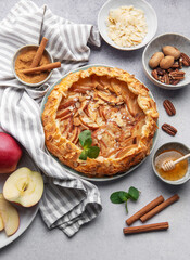Delicious apple tart with almonds and honey served on a rustic table with fresh apples and spices