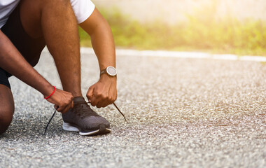Close up Asian sport runner black man wear watch sitting he trying shoelace running shoes getting ready for jogging and run outdoor street health park with copy space, healthy exercise workout concept