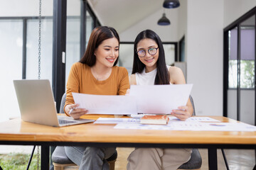 young asian businesswoman working on laptop with finances analysis report at desk in office, business financing, accounting banking,