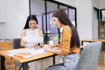 young asian businesswoman working on laptop with finances analysis report at desk in office, business financing, accounting banking,