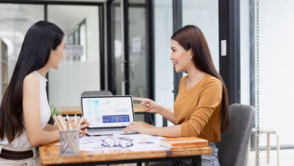 young asian businesswoman working on laptop with finances analysis report at desk in office, business financing, accounting banking,