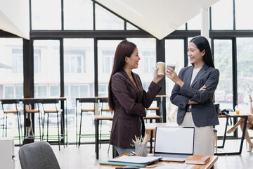 Two Asian business female talking together with partner standing in office. 