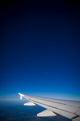 Wing of modern aircraft, beautiful blue sky with moon