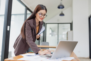 Asian businesswoman working on laptop with finances analysis report at desk in office, business financing, accounting banking,