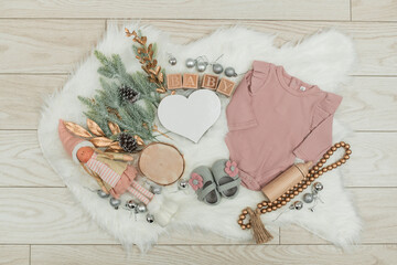 A cozy holiday-themed pregnancy announcement setup with a baby onesie, doll, and festive...