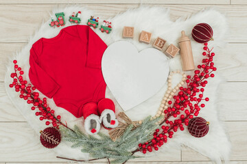 Festive baby announcement setup featuring a baby onesie, a letterboard, and seasonal holiday...