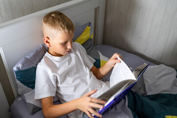 fair-haired teenage boy reading a book before bed