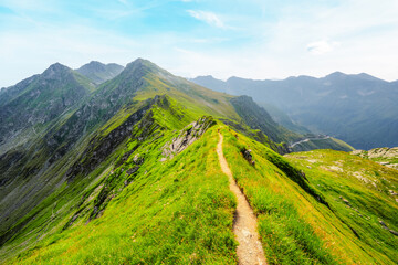 Fototapeta premium Hiking in Fagaras mountains on Iezerul Caprei peak over Transfagarasan serpentine road carpathian mountains. Mountains landscape