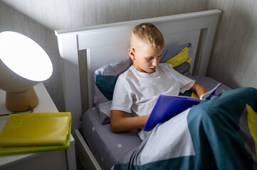 fair-haired teenage boy reading a book before bed