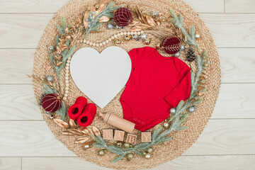 Festive baby announcement setup featuring a baby onesie, a letterboard, and seasonal holiday...