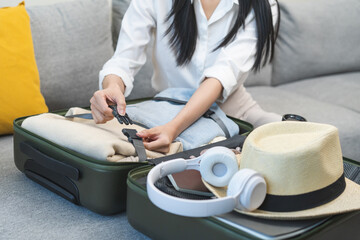 Vacation, holiday travel, traveler asian young woman, girl strap belt, packing, buckle preparing stuff into luggage or baggage bag case for journey trip, preparation for journey voyage at home