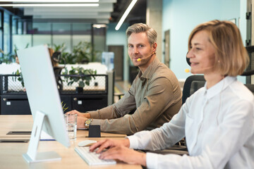 Attractive positive young businesspeople and colleagues in a call center office.
