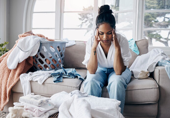 Fatigue, headache and woman on sofa with laundry, housework schedule and chaos in washing. Stress,...