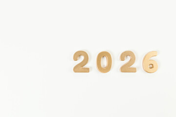 2026 Happy New Year. Top view of gold numbers on white background. Copy space, flat lay.