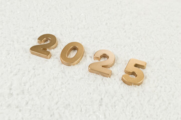 2025 Happy New Year. Top view of gold numbers on white snow background. Copy space, flat lay.