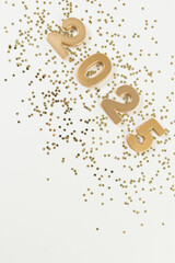 2025 Happy New Year. Top view of gold numbers, gold stars confetti on white background. Copy space, flat lay.