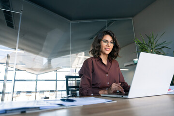 Young businesswoman professional employee using pc doing online banking analysing at workplace. Latin hispanic middle age business woman working on laptop computer in modern office. Banner, copy space