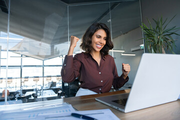 Happy excited young businesswoman looking at laptop pc computer screen doing yes triumph win...