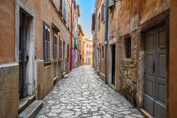 Fotobehang Smal steegje Rovinj, Croatia - Empty narrow street at the Old Town of Rovinj in a sunny summer morning with traditional cobblestones, colorful houses, windows and doors  © zgphotography
