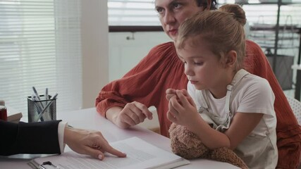 Handheld shot of counselor talking to mother about social aid contract during visit at social office with daughter