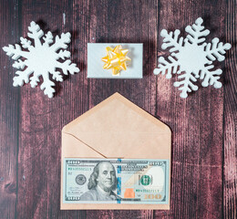 Money present 20 dollars, snowflakes and giftbox on a brown wooden background, top view, copy space