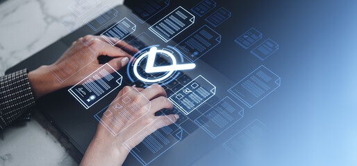 Hands typing on a laptop with digital document icons and a check mark overlay. Futuristic blue background. Concept of online document approval