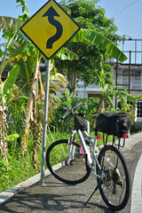 White touring bike at the street with winding road sign