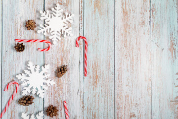 Christmas decorations on a wooden background: Christmas tree balls, branches, snowflakes and candy canes, top view, copyspace
