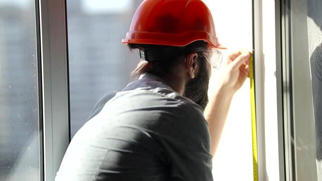 Construction worker measuring window with precision 