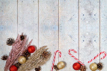 Christmas decorations on a wooden background: Christmas tree balls, branches, snowflakes and candy canes, top view, copyspace