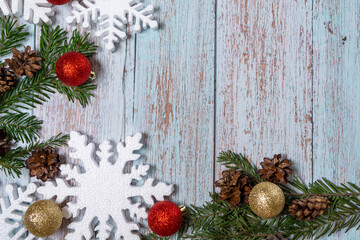 Christmas decorations on a wooden background: Christmas tree balls, branches, snowflakes and candy canes, top view, copyspace