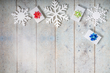 White decorative snowflakes and giftbox on a wooden background, copy space