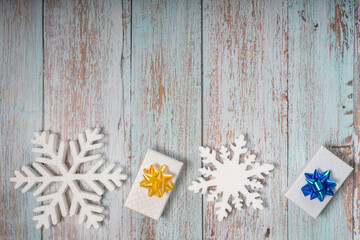 White decorative snowflakes and giftbox on a wooden background, copy space