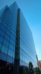 Obraz premium Modern office building with sleek glass facade against a clear blue sky, modern, exterior