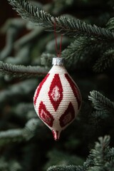 Obraz premium A red and white Christmas tree ornament hangs from the branches