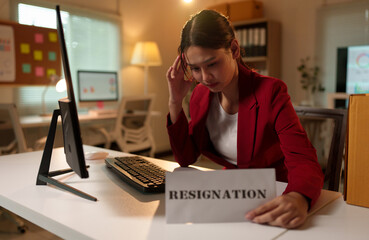 Attractive Asian businesswoman is sitting at a desk holding a resignation letter at her desk inside the office. failed work concept unsuccessful Changing careers, job positions.