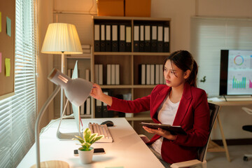 Asian businesswoman working using PC computer in modern office Freelance female employee reports online marketing Analyze reports from data files startup business idea working overtime.