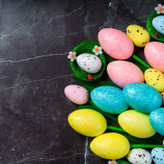 Easter background with copyspace. Colorful tulips and decorative eggs on black granite, top view