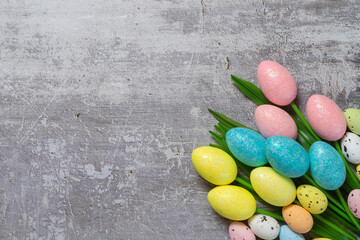 Easter background with copyspace. Colorful tulips and decorative eggs on concrete, top view