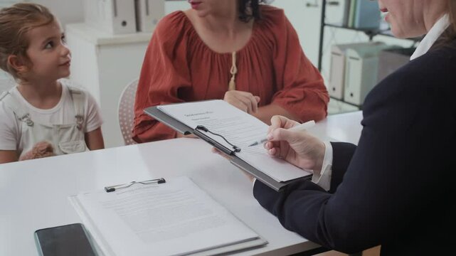 Cropped shot of female social worker holding paper with questions about living conditions of mother and daughter visiting office to get social aid