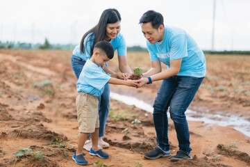 family of three, a man and two children, are planting a tree together