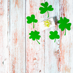 Green four leaf clovers and giftbox on white wooden background top view. Happy St. Patrick's Day...