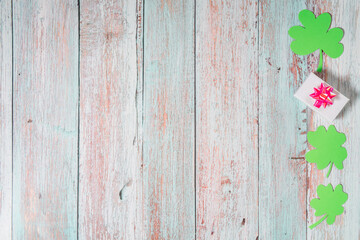 Green four leaf clovers and giftbox on white wooden background top view. Happy St. Patrick's Day greetings