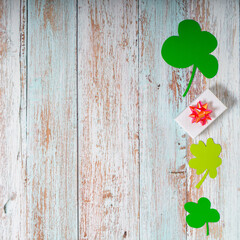 Green four leaf clovers and giftbox on white wooden background top view. Happy St. Patrick's Day...