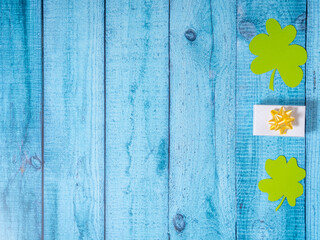 Green four leaf clovers and giftbox on white wooden background top view. Happy St. Patrick's Day...