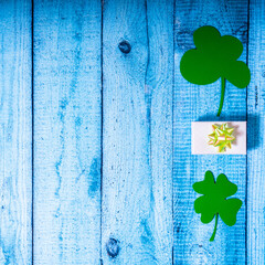 Green four leaf clovers and giftbox on white wooden background top view. Happy St. Patrick's Day...