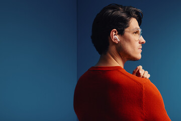 Man wearing wireless earbuds in colorful studio shot
