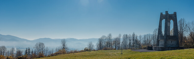 Fototapeta premium Wide panorama of World war 2 memorial erected by partisans above the village of Stari Trg pri Lozu on Ulaka hill. Visible stone structure on a sunny autumn day..