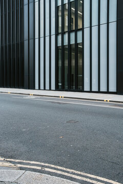 A sleek, modern building facade featuring vertical black and white panels with a foreground view of an empty street, representing urban architecture style.