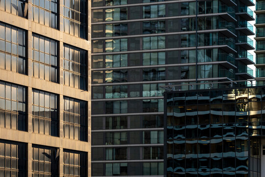 This image showcases several city buildings with sunlight reflecting off the glass surfaces, creating an abstract interplay of light, shadow, and reflections.